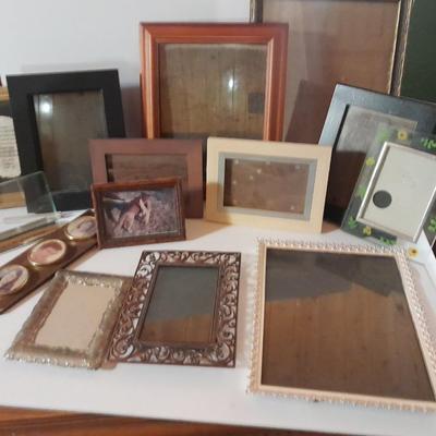 Variety of picture frames, some wood, some metal