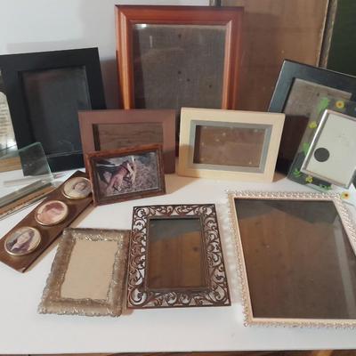 Variety of picture frames, some wood, some metal