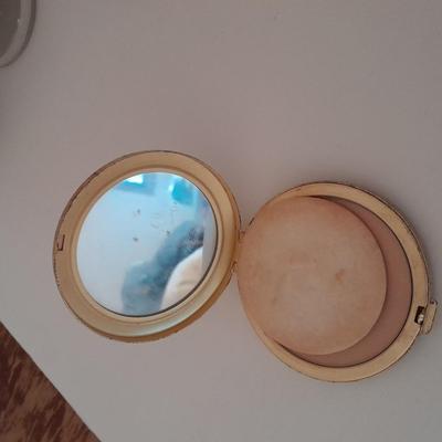 Vanity top mirror with gold rim, brass lidded jars and a compact