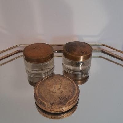 Vanity top mirror with gold rim, brass lidded jars and a compact