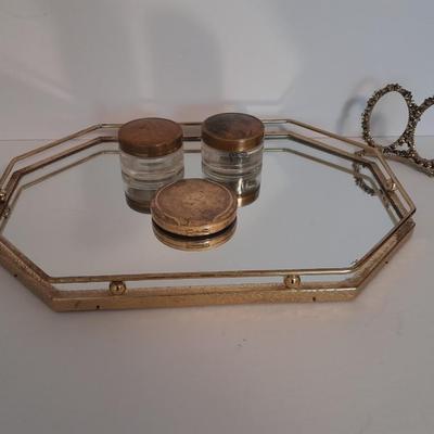 Vanity top mirror with gold rim, brass lidded jars and a compact