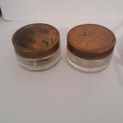 Vanity top mirror with gold rim, brass lidded jars and a compact