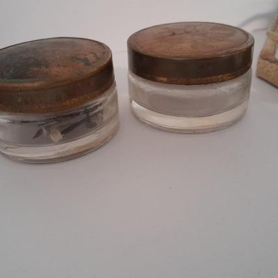 Vanity top mirror with gold rim, brass lidded jars and a compact