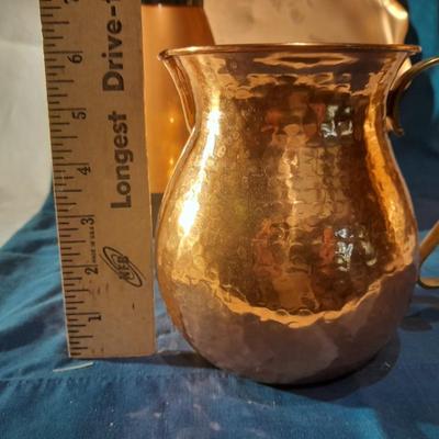 Copper and copper toned hot and cold pitchers on copper platter
