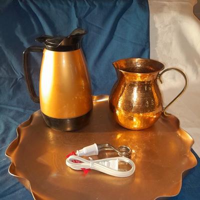 Copper and copper toned hot and cold pitchers on copper platter