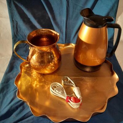 Copper and copper toned hot and cold pitchers on copper platter