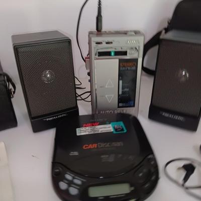 Portable Sony CD Car Discman with remote and vehicle attachments, a pair of Realistic speakers with case, and a Aiwa Walkman