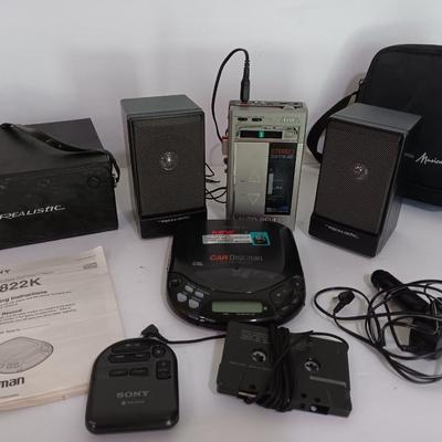 Portable Sony CD Car Discman with remote and vehicle attachments, a pair of Realistic speakers with case, and a Aiwa Walkman
