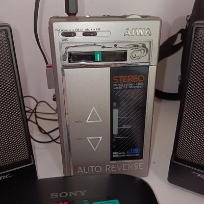 Portable Sony CD Car Discman with remote and vehicle attachments, a pair of Realistic speakers with case, and a Aiwa Walkman