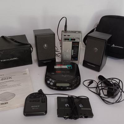 Portable Sony CD Car Discman with remote and vehicle attachments, a pair of Realistic speakers with case, and a Aiwa Walkman
