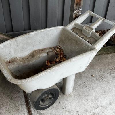 Behind GARAGE -- Plastic wheel barrow