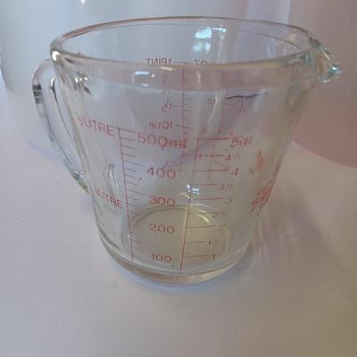 Three plastic lidded food storage containers with Fire King measuring glass