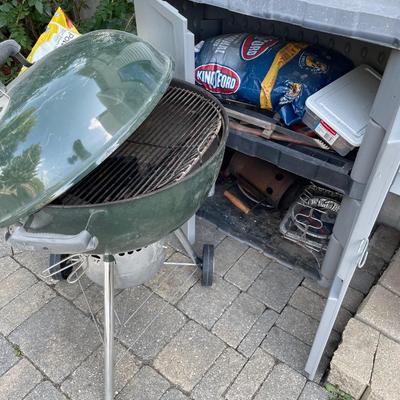Green Weber grill with outdoor storage and grill accessories