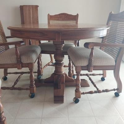 WOODEN TABLE AND FOUR ARMCHAIRS WITH CASTORS AND TWO EXTENSION LEAVES