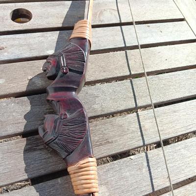 Hand carved two faced Native American head archery decorative bow with arrows.