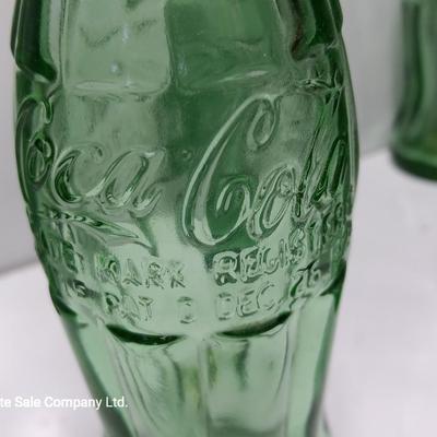 Six glass Coca Cola bottles and small coca cola collectible tin