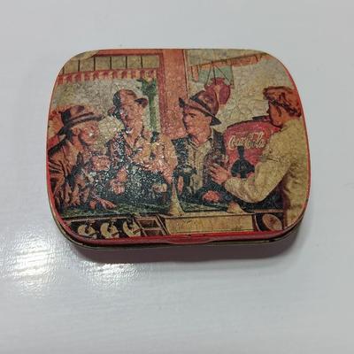 Six glass Coca Cola bottles and small coca cola collectible tin