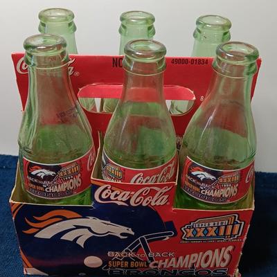 Denver Bronco's Back-to-Back Superbowl coca cola bottles in case with a Bronco's towel and Christmas hat