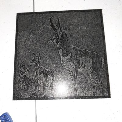 Four different pocketknives and a lasered antelope on tile