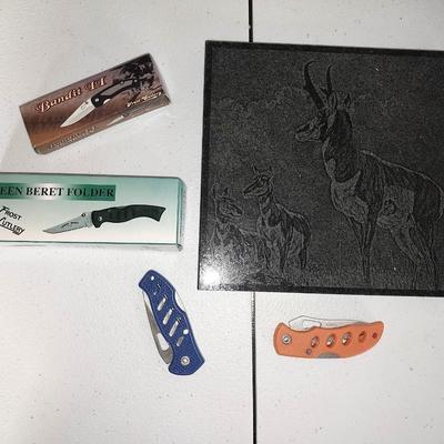 Four different pocketknives and a lasered antelope on tile