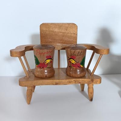 Cast Iron Rooster napkin holder with chicken theme salt & pepper on a bench.