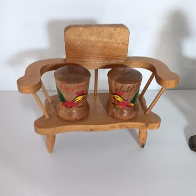 Cast Iron Rooster napkin holder with chicken theme salt & pepper on a bench.