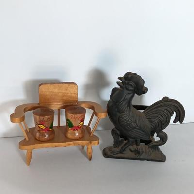 Cast Iron Rooster napkin holder with chicken theme salt & pepper on a bench.
