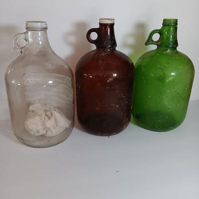 Three vintage glass gallon jugs each with a handle