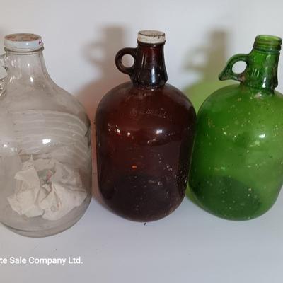 Three vintage glass gallon jugs each with a handle