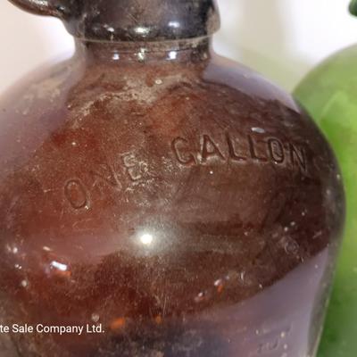 Three vintage glass gallon jugs each with a handle