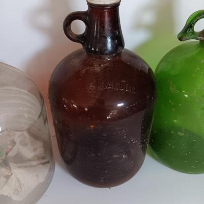 Three vintage glass gallon jugs each with a handle