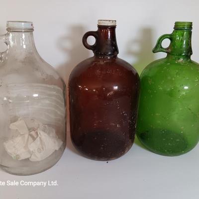Three vintage glass gallon jugs each with a handle