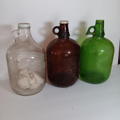 Three vintage glass gallon jugs each with a handle