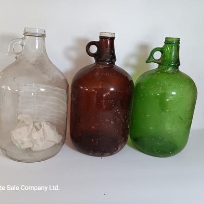 Three vintage glass gallon jugs each with a handle