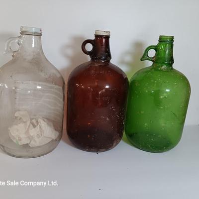 Three vintage glass gallon jugs each with a handle