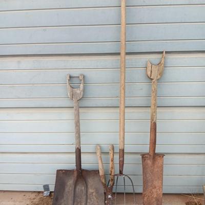 Two antique shovels with wood handles an old pitchfork and some trimmers