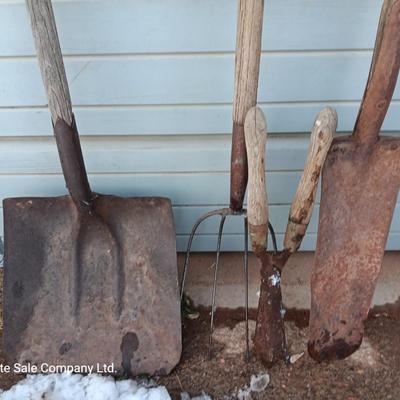 Two antique shovels with wood handles an old pitchfork and some trimmers