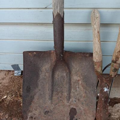 Two antique shovels with wood handles an old pitchfork and some trimmers