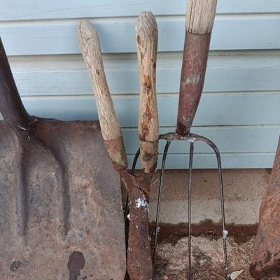 Two antique shovels with wood handles an old pitchfork and some trimmers
