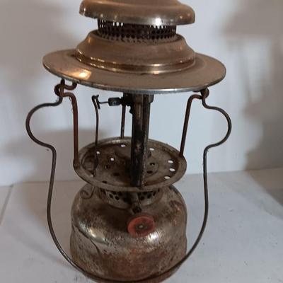 two vintage lanterns for repair with a metal container of camp fuel