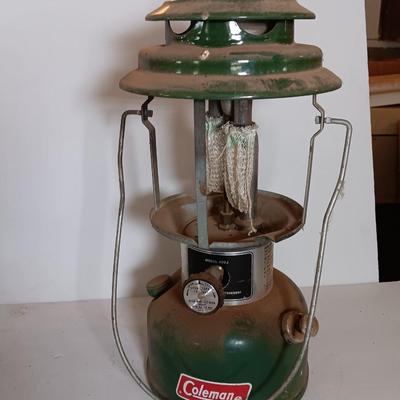 two vintage lanterns for repair with a metal container of camp fuel