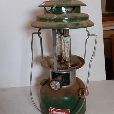 two vintage lanterns for repair with a metal container of camp fuel