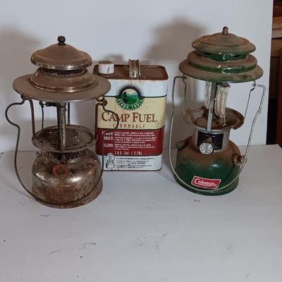 two vintage lanterns for repair with a metal container of camp fuel
