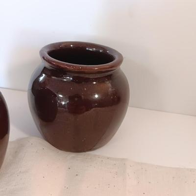 Four small brown crock bowls with embroidered linen
