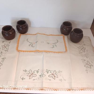 Four small brown crock bowls with embroidered linen