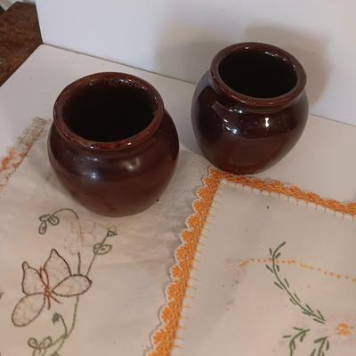 Four small brown crock bowls with embroidered linen