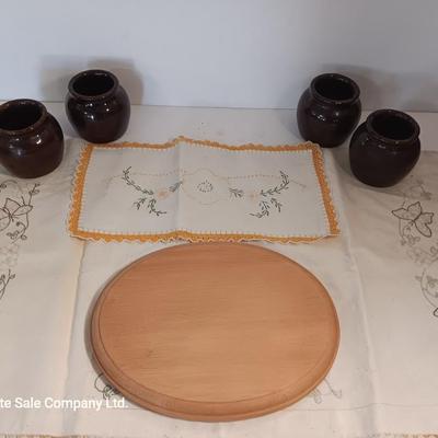Four small brown crock bowls with embroidered linen
