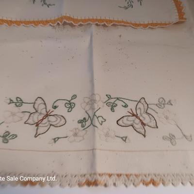 Four small brown crock bowls with embroidered linen