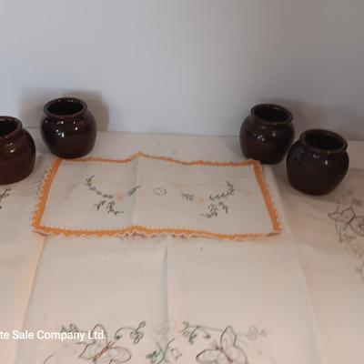Four small brown crock bowls with embroidered linen