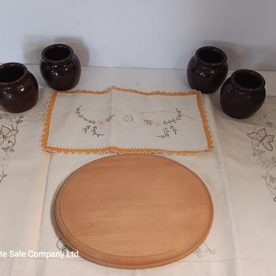 Four small brown crock bowls with embroidered linen